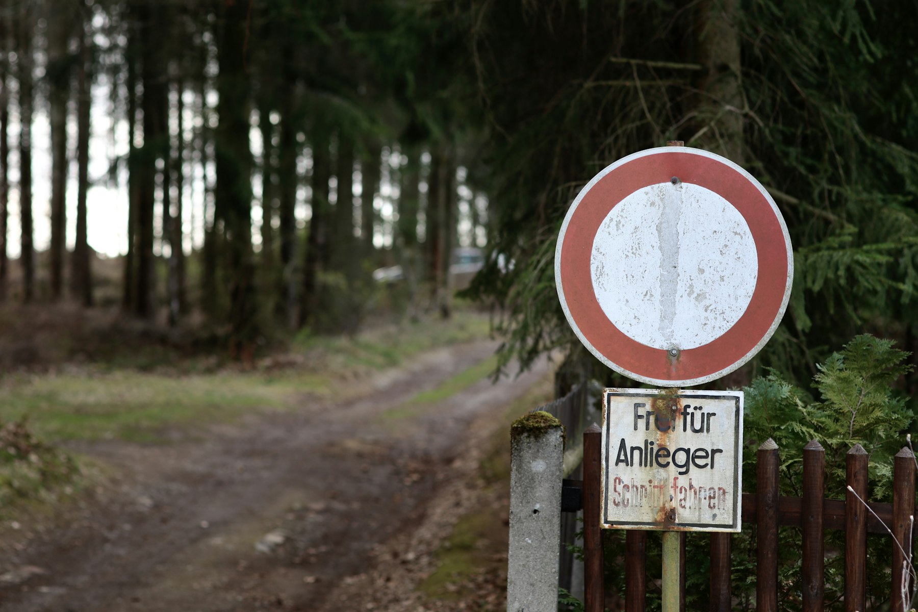 Verschmutztes Verkehrsschild „Verbot für Fahrzeuge aller Art“ mit Zusatzzeichen „Frei für Anlieger“ an einem Waldweg